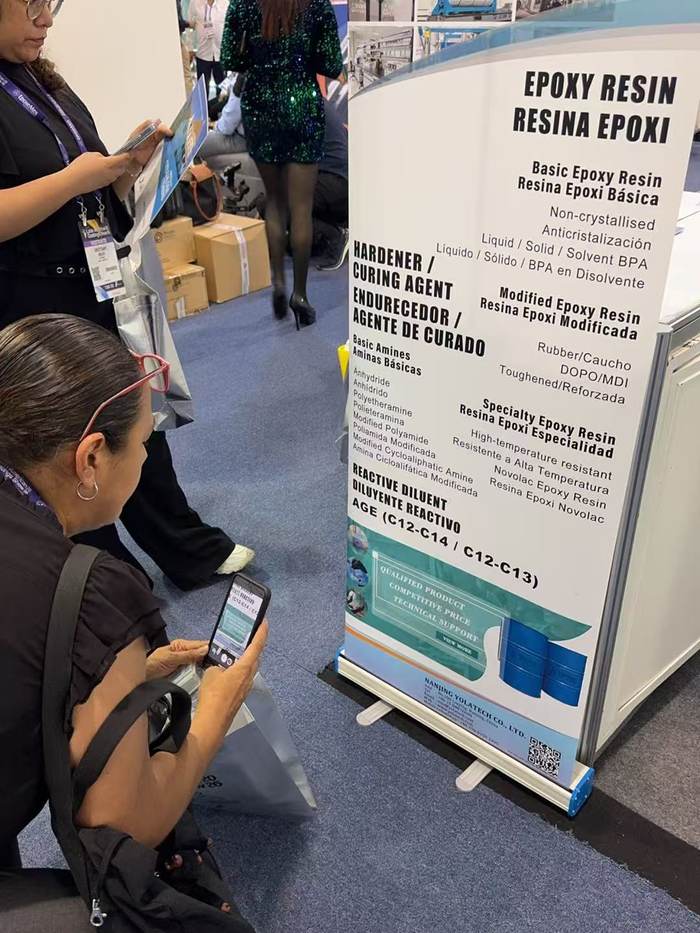 Visitors reading the Yolatech epoxy hardener and reactive diluent panel at LACS 2026