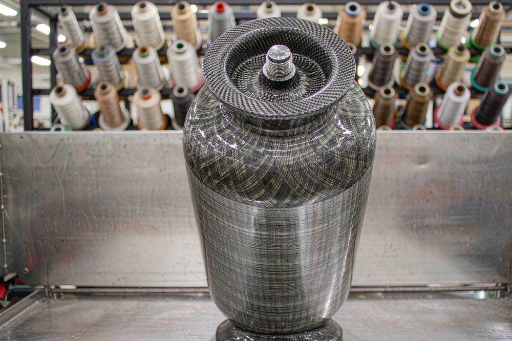 finished carbon fibre pressure vessel with a wound epoxy surface standing in a composite workshop